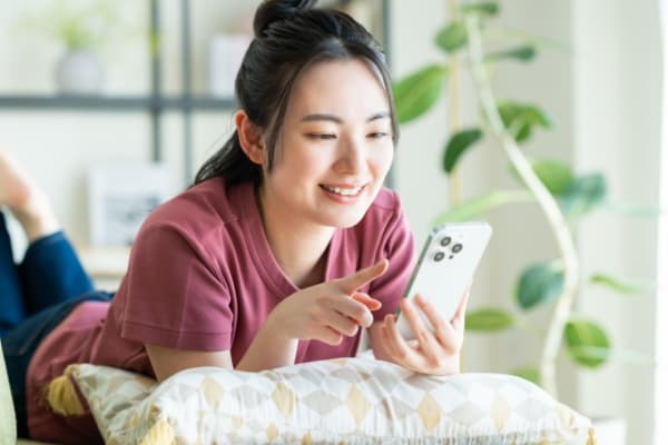寝っ転がってスマホを操作する女性